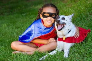 Little girl and dog dressed up in matching superhero costumes for Halloween